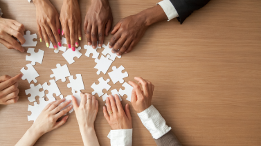 A group of people assembling a puzzle together, showing teamwork